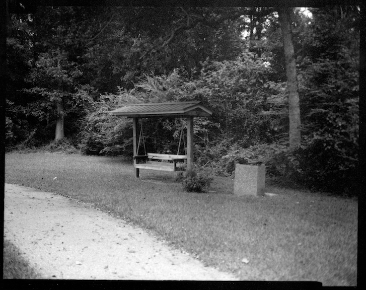 Black and White photograph of a covered swinging bench.