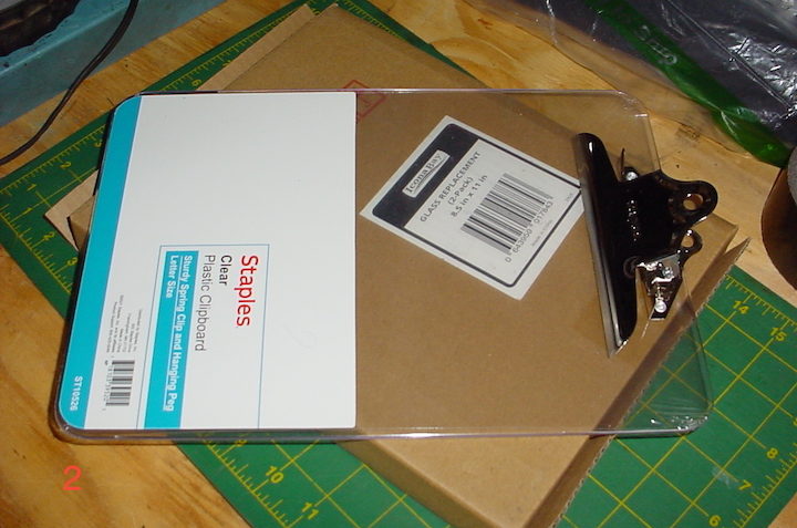 Photograph of a clear plastic clipboard and a cardboard box